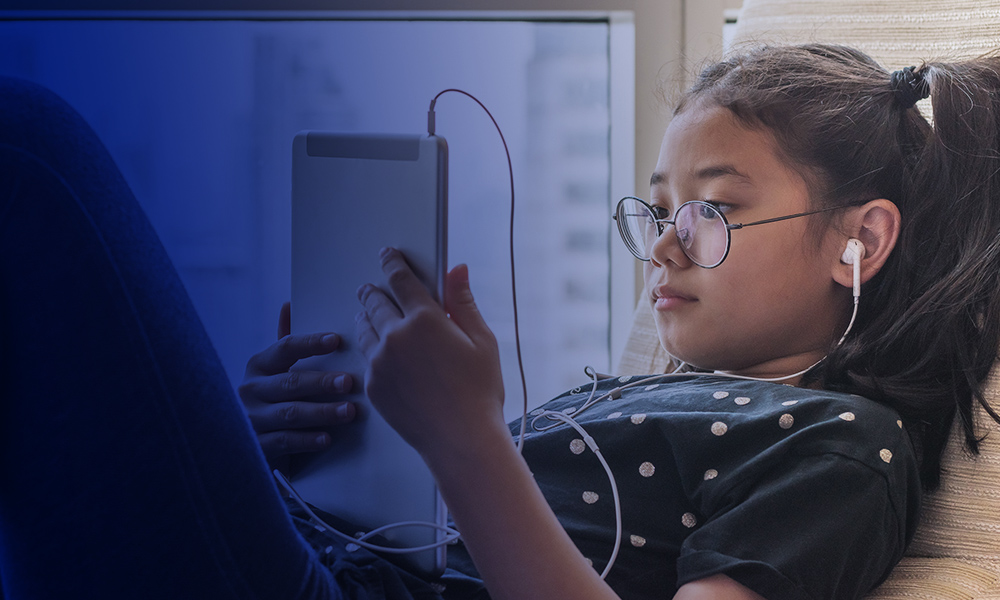 A little girl reading on an iPad.